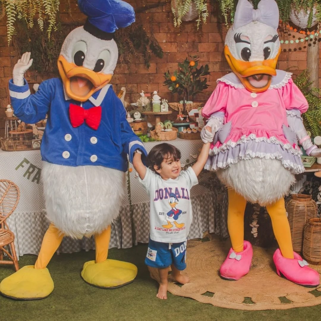 Criança ao lado de personagens em festa infantil no quintal